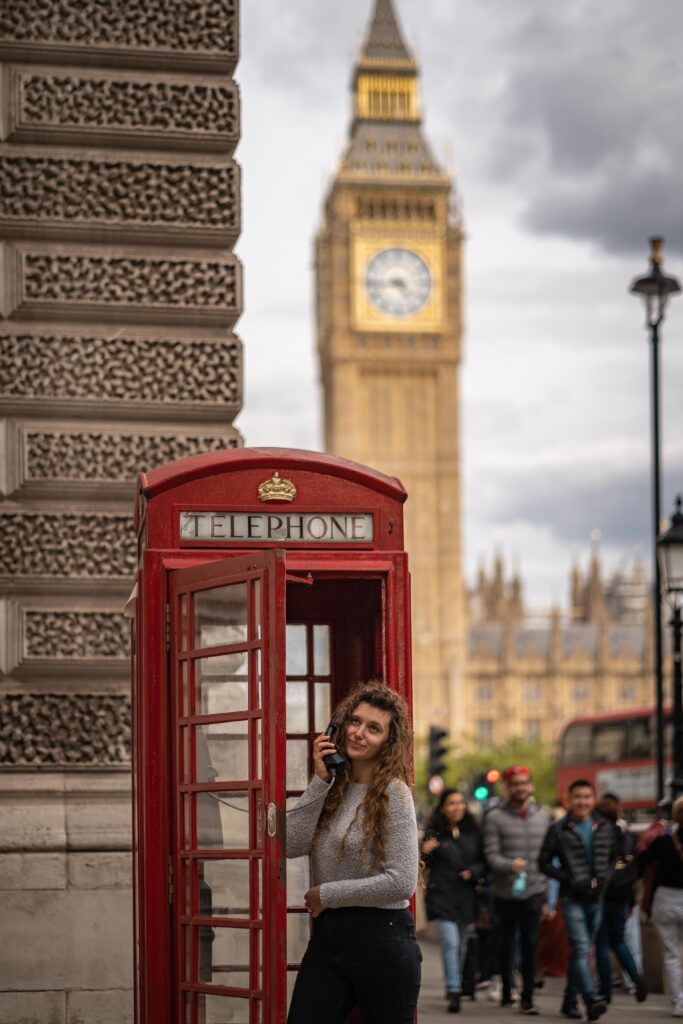 Dziewczyna w czerwonej budce telefonicznej na tle Big Bena w Londynie